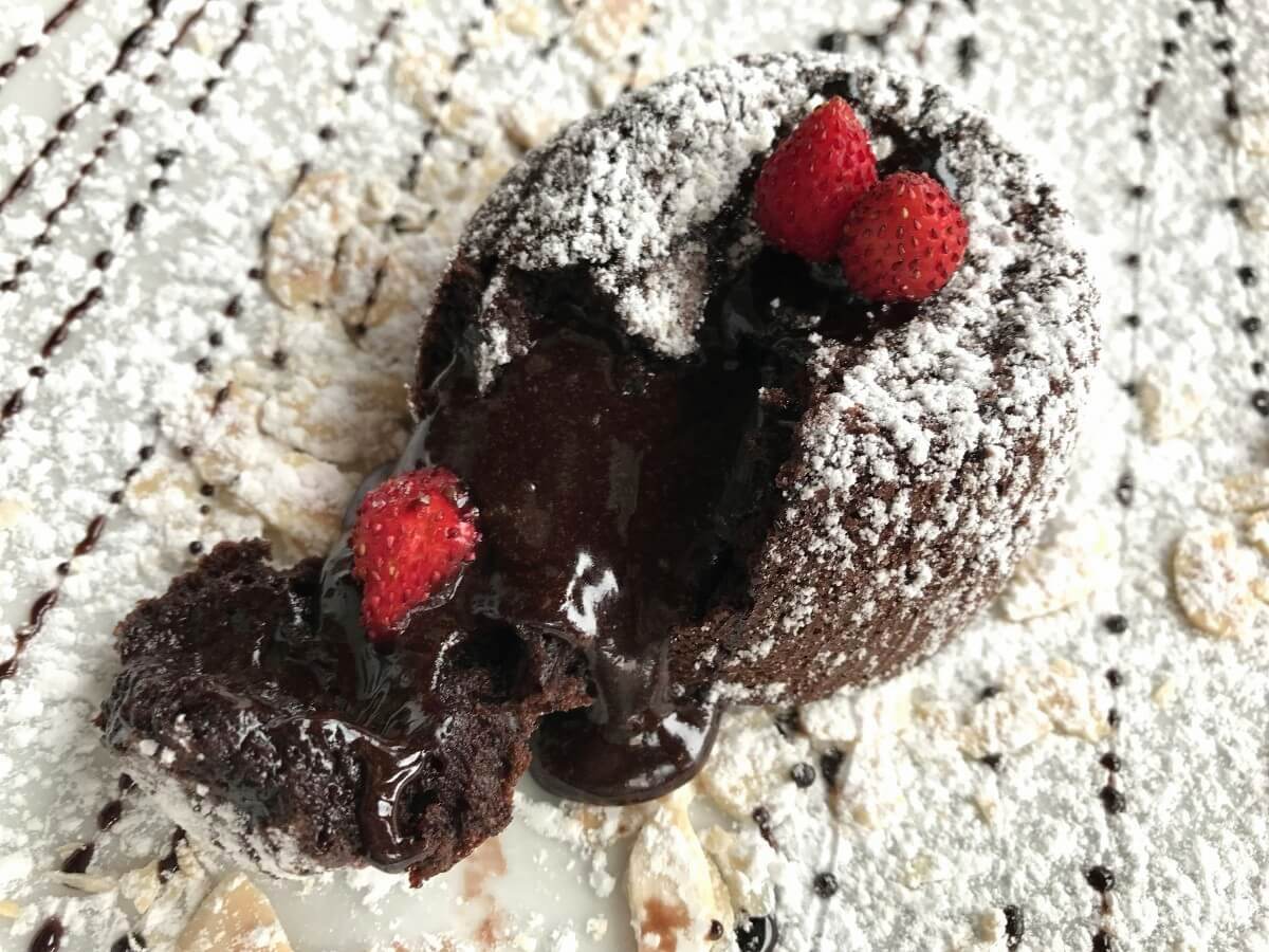 Petit gâteau relleno de chocolate fundido con azúcar impalpable y almendras sicilianas