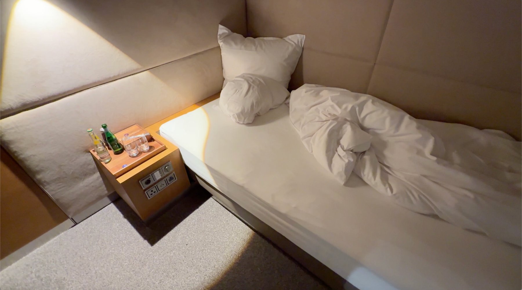 First Class Lounge de Lufthansa en Munich una cama con cobijas blancas
